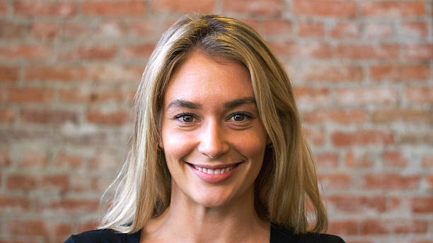 portrait of smiling caucasian woman standing against brick wall in coffee shop